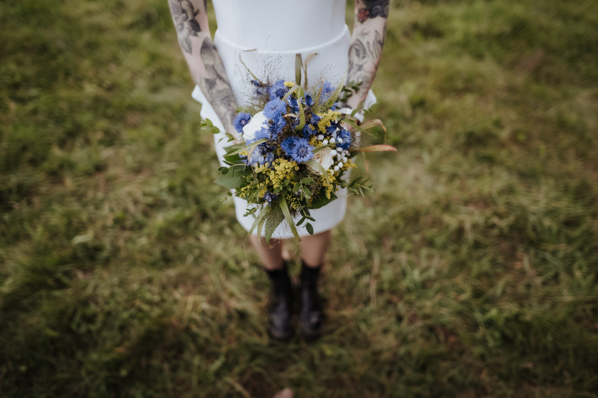 Brautstrauß mit blauen Blüten und Boots – alternative Brautmode für unkonventionelle Hochzeiten im Grünen