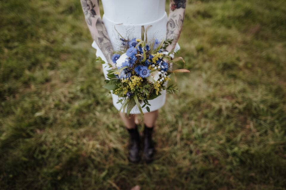 Brautstrauß mit blauen Blüten und Boots – alternative Brautmode für unkonventionelle Hochzeiten im Grünen