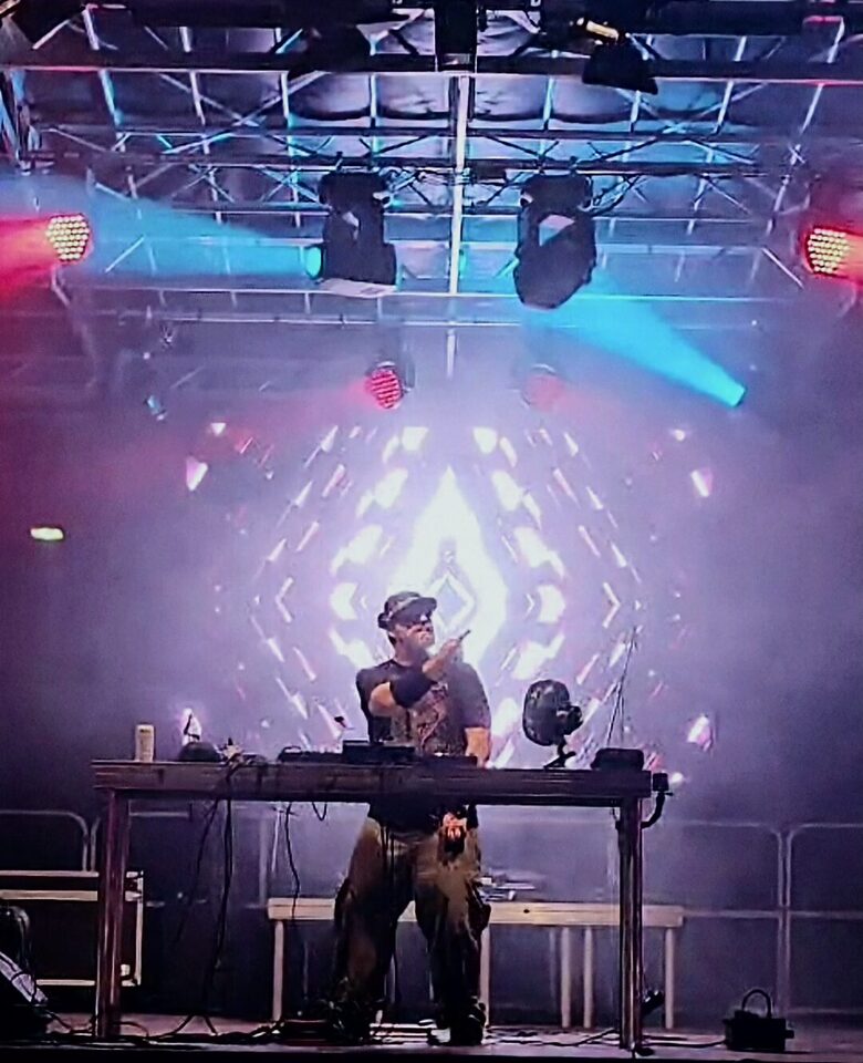 Tom Nawa Events steht als alternativer Hochzeits-DJ am DJ-Pult vor heller Lichtshow und sorgt für Party-Stimmung bei einer alternativen Hochzeit.