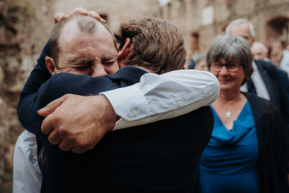 Emotionale Umarmung mit Vaterfigur – authentischer Hochzeitsmoment, voller Nähe und echter Gefühle