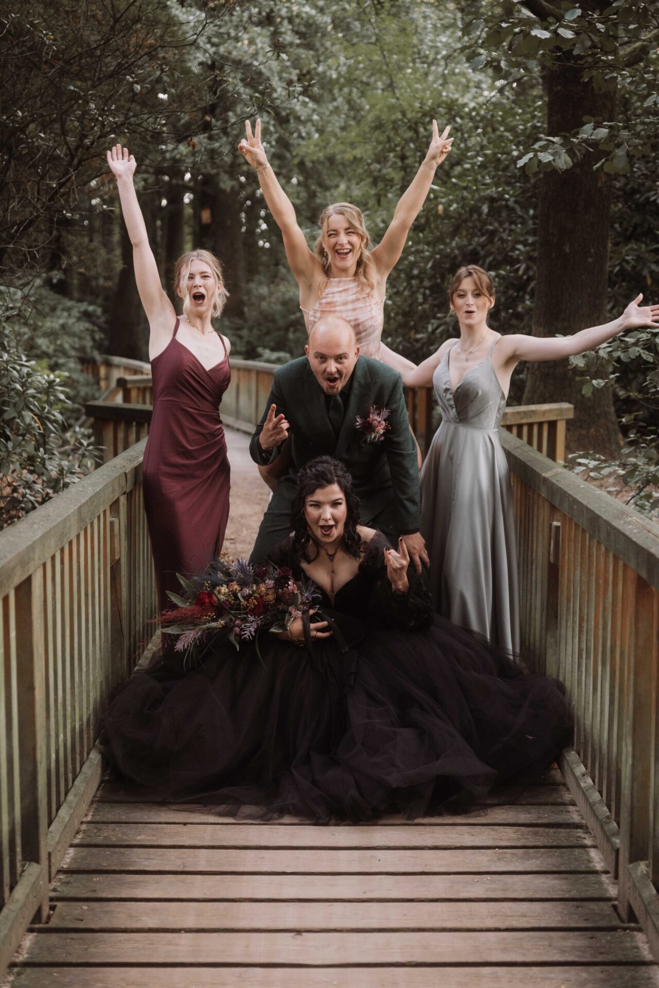 Bridal Party auf der Holzbrücke mit Rock-Posen – Gruppenfoto für eine alternative Hochzeit, fotografiert von Patricia Bakker.