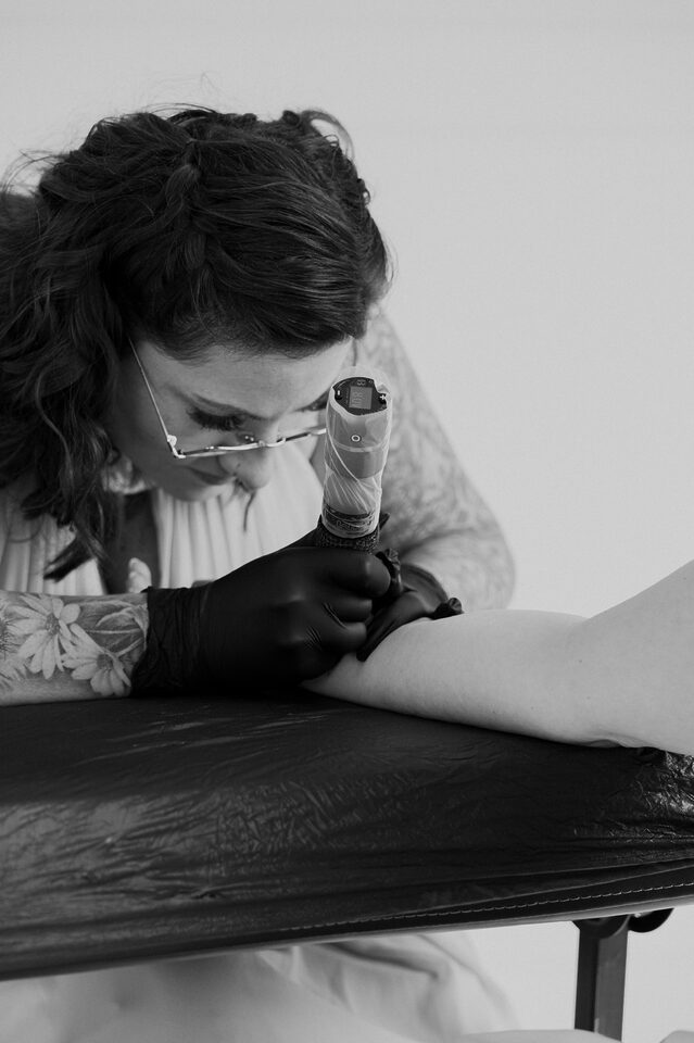 Tattooartist Dannii tätowiert bei einer Hochzeit den Unterarm eines Gastes.